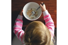 Image Little girl eating bowl of cereals for breakfast